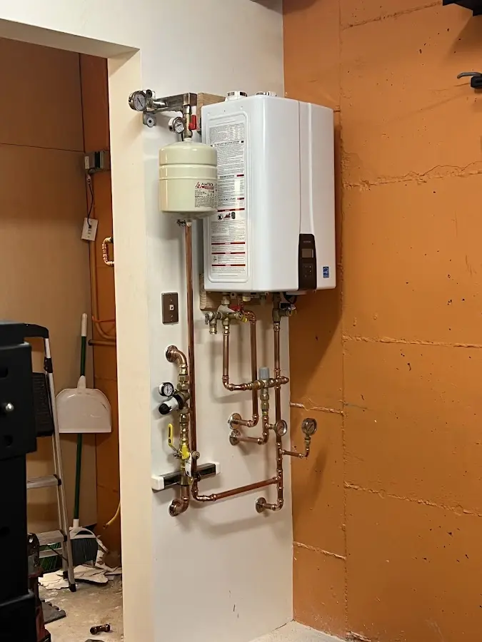 Plumbing technician inspecting water heater connections in Farmington